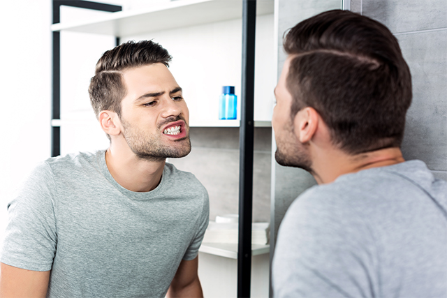 鏡で歯を確認する男性