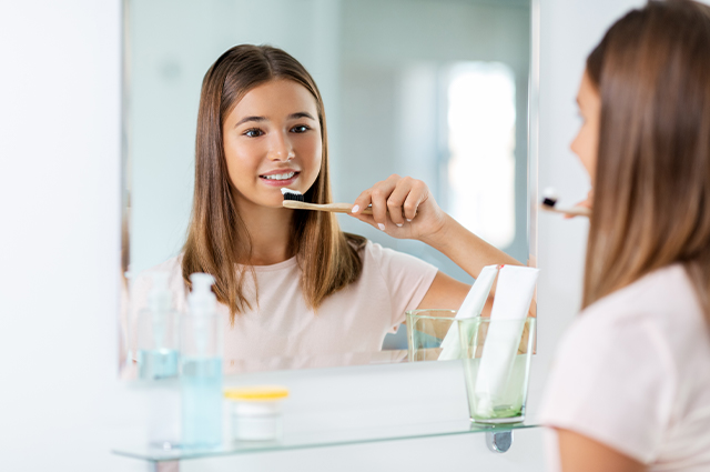 鏡を見ながら歯磨きする女性