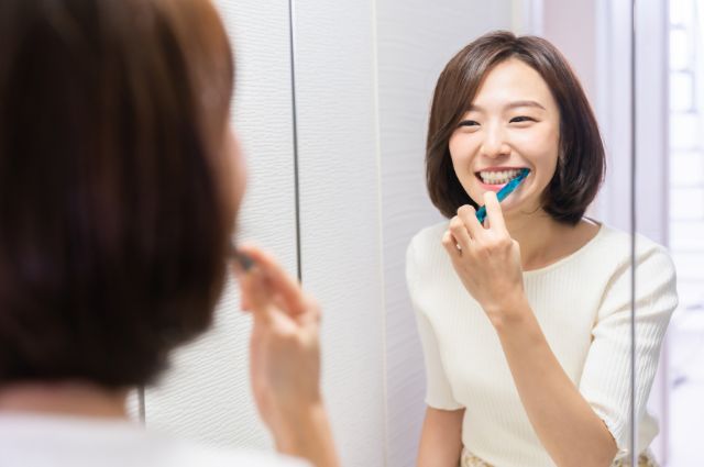 鏡を見ながら歯磨きする女性