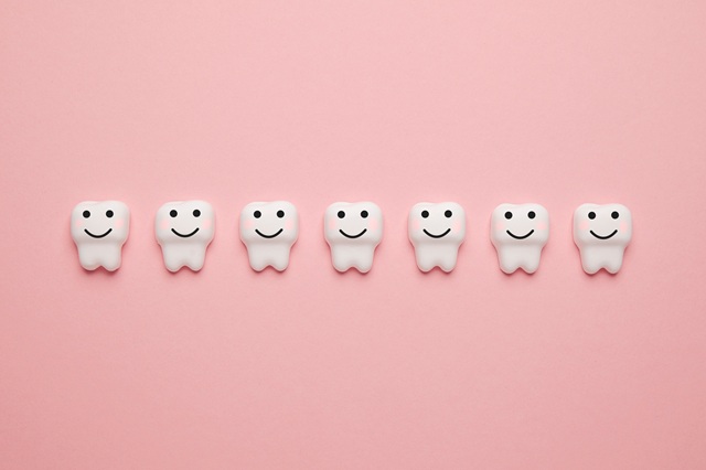 ピンクの背景に並んでいる顔がついた歯