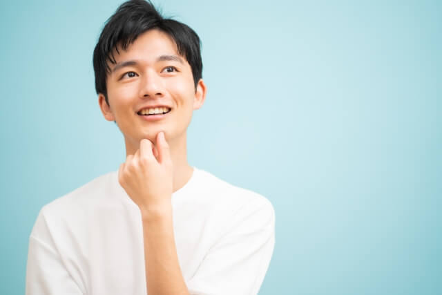 顎に手を当てて笑う若い男性